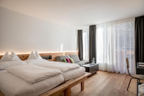 1 dormitorio con 1 cama blanca grande y 1 sofá en die berge lifestyle-hotel sölden, en Sölden