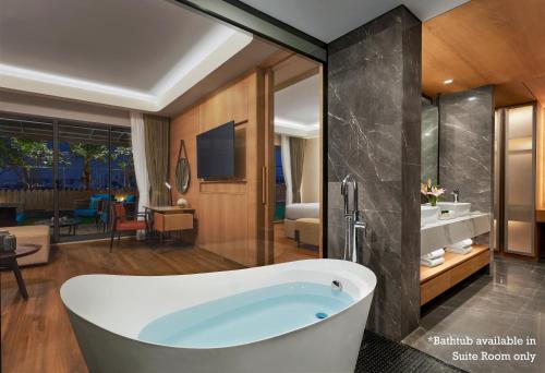 a bathroom with a tub and a living room at Hyatt Place Vadodara in Vadodara