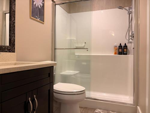a bathroom with a toilet and a glass shower at Bright New 2BR Suite Near YVR in Vancouver
