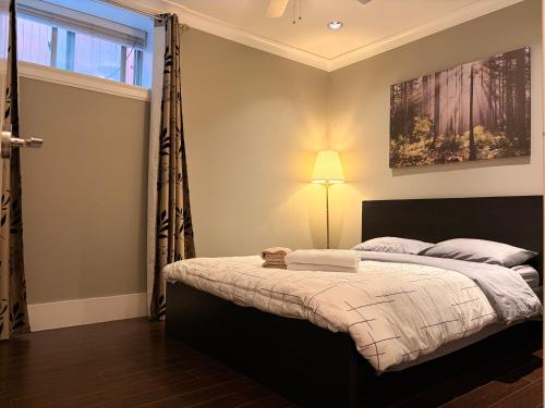a bedroom with a bed with a lamp and a window at Bright New 2BR Suite Near YVR in Vancouver