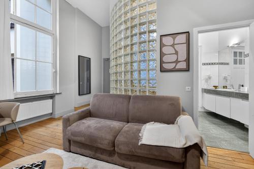 a living room with a couch and a large window at Maison Lombard by Reside in Brussels