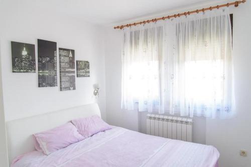 a white bedroom with a bed and a window at Apartman Sinisa in Zlatibor