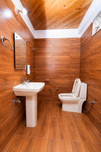 a bathroom with a sink and a toilet and wooden walls at Babutaal Resort in Chakrāta