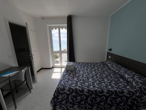 a bedroom with a bed and a table and a window at Hotel Aurora in Varazze