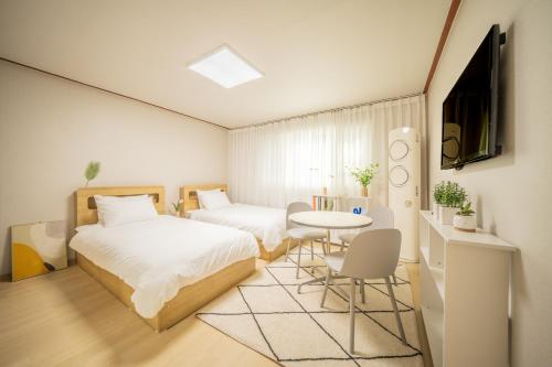 a bedroom with two beds and a table and a tv at 선스테이 in Ilsan-ni