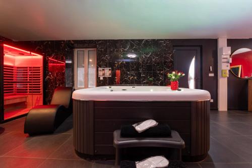 a bathroom with a tub and two chairs and a tub at Le Cocon secret - Sauna - Jacuzzi in Quimperlé