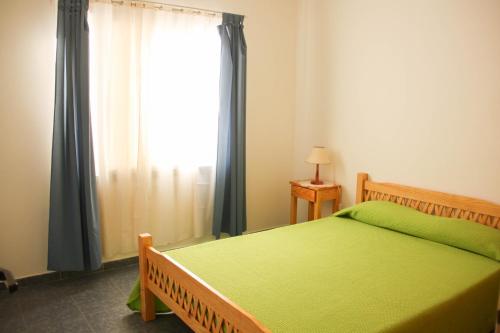 Un dormitorio con una cama verde y una ventana en Casa en Balneario Sol y Rio en Villa Carlos Paz
