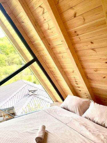 a bed in a room with a large window at SkyFrame cottage with pool in Plav