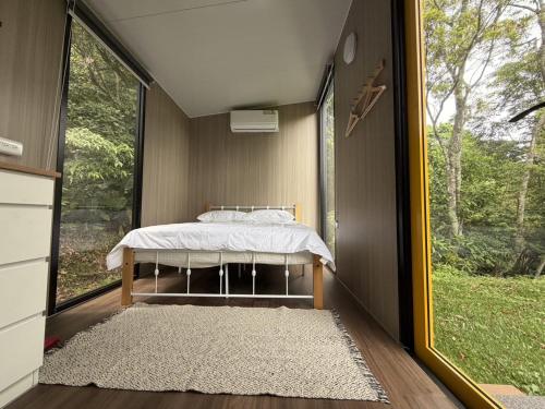 a bedroom with a bed and a large window at Mountain Calm Inns in Xiayun