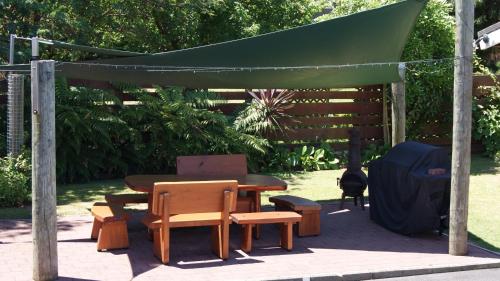 a picnic table and chairs under a green canopy at Tourist Court Motel in Whakatane