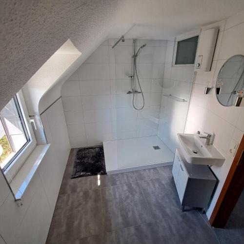 a white bathroom with a shower and a sink at Nest and Nature Strauch in Simmerath