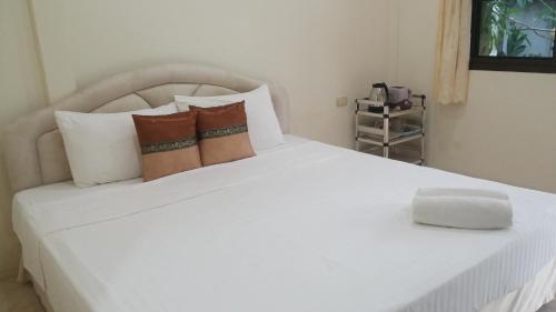 a white bed with pillows and a white box on it at Wattana Bungalow in Nai Yang Beach