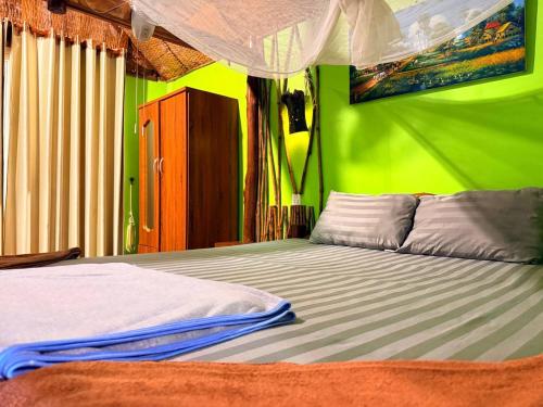 a bedroom with a bed with a green wall at Sunny Bungalow in Koh Rong Sanloem