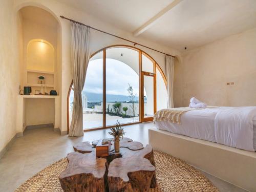 a bedroom with a bed and a large window at Holista Bali in Kubupenlokan