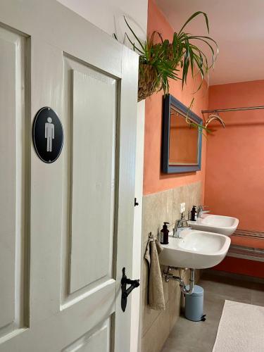 a bathroom with two sinks and a white door at Pilgerhaus Wildsteig in Wildsteig