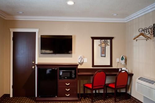 a room with two red chairs and a desk with a television at Budget Inn Anaheim near Disneyland Drive in Anaheim