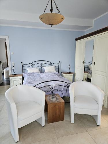 a bedroom with a bed and two white chairs at "Zweisam" am Scharmützelsee - Ferienwohnung mit mediterranem Charme in Diensdorf-Radlow