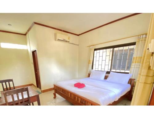 a bedroom with a bed with a red flower on it at Johnny Guesthoues and Restaurant in Ban Donsôm Tai