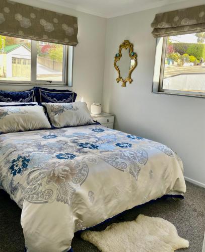 a bedroom with a bed with a blue and white comforter at The Penguins Nest in Oamaru