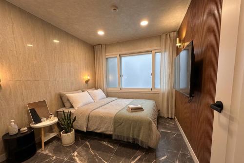 a small bedroom with a bed and a window at Billy Hostel in Busan