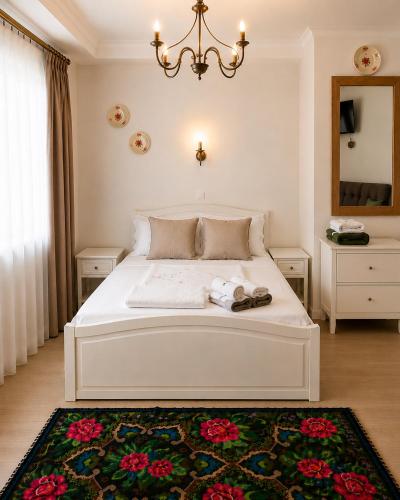 a bedroom with a white bed with a chandelier at Conacul Birtoc Refugiu Tradițional în Maramureș in Văleni