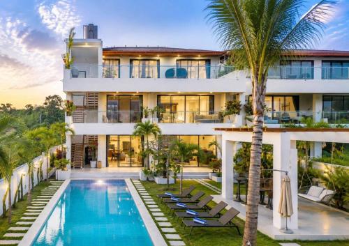 an exterior view of a building with a swimming pool and palm trees at Gandum Villa Complex - Luxury Boutique Stay Uluwatu in Uluwatu