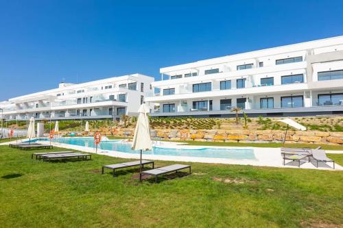 a large apartment building with a pool and an umbrella at Doña Julia Sea View Marvel in Casares