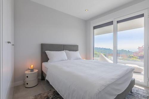 a white bedroom with a large bed and a large window at Doña Julia Sea View Marvel in Casares