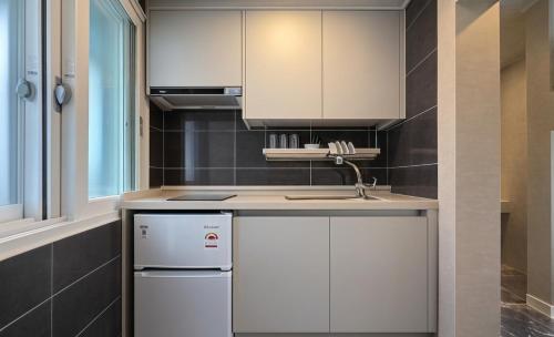 a kitchen with white cabinets and a sink at Billy Hostel in Busan