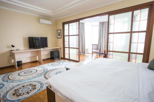 1 dormitorio con 1 cama grande y TV en Apartment 5, en Almaty