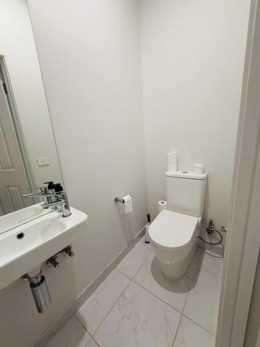 a white bathroom with a toilet and a sink at Feels Like Home in Wyndham Vale