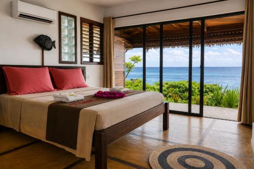 a bedroom with a bed with a view of the ocean at Manga Soa Lodge in Fascène - Befefika