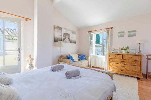 a white bedroom with a large bed and a dresser at la maison des Olivettes in Uzès