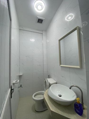 a white bathroom with a sink and a toilet at Villa El Marie in Bacnotan