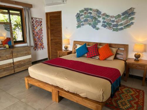 a bedroom with a large bed with colorful pillows at Village des Iles in Praslin