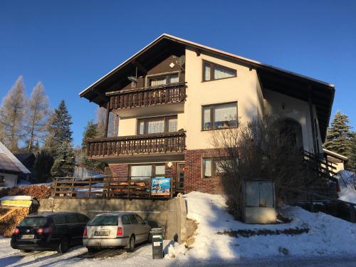 a large house with two cars parked in the snow at Penzion Janouškovi in Harrachov