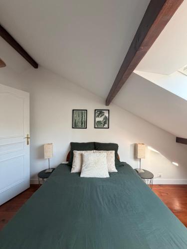 a bedroom with a large green bed with two lamps at Chambre 24h Le Mans in Guécélard