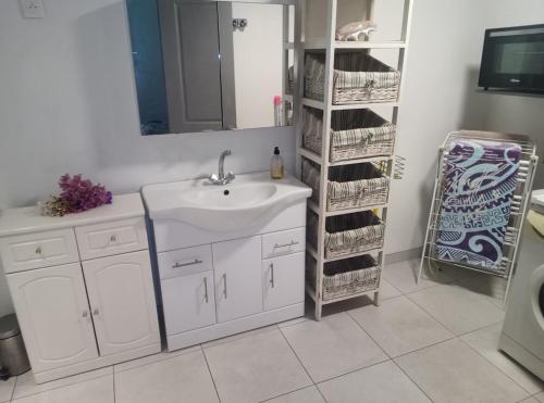 a bathroom with a sink and a shelf with towels at Chez Teivama in Haapiti