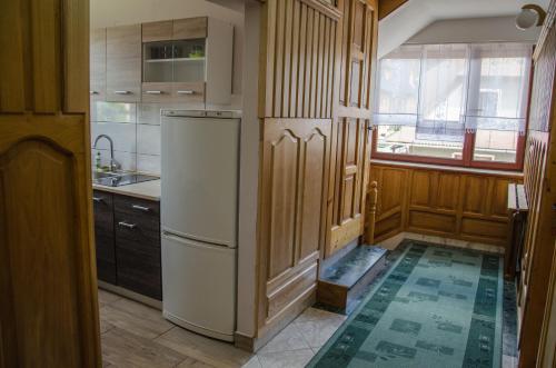 a kitchen with a refrigerator and wooden cabinets at Pokoje Gościnne Anna in Poronin