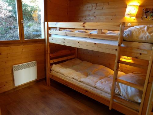 2 Etagenbetten in einem Blockhaus mit einem Fenster in der Unterkunft Chalet Daria in Prémanon