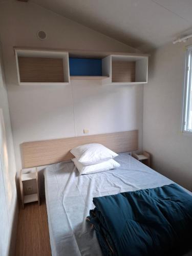 a small bedroom with a bed with a blue blanket at Camping Les Peupliers in Saint-Père-en-Retz