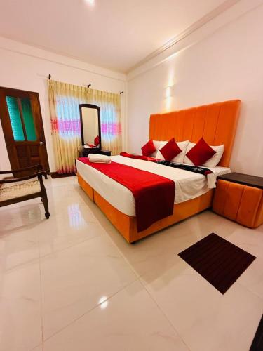 a bedroom with a large bed with red pillows at Little England Grand Hotel in Nuwara Eliya