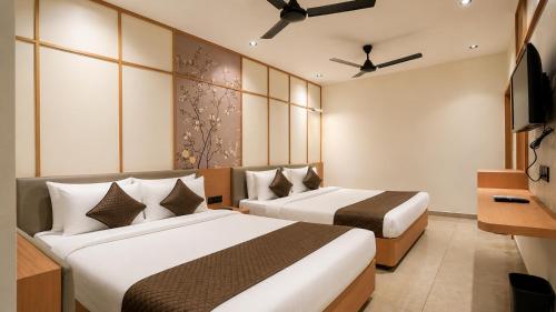a hotel room with two beds and a television at Hotel Rushikesh inn Dwarka in Dwarka
