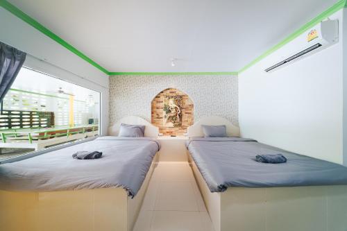 two beds in a room with a window at แฝดสามการ์เด้นท์รีสอร์ท แสมสาร Fadsarm Garden Resort Samaesan in Sattahip