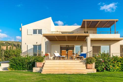 a house with a deck with a table and chairs at Legrena Beach Villa in Sounio