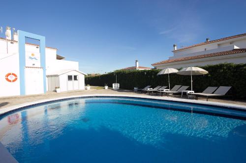 a large blue swimming pool in front of a house at Nuvolet Apartaments in Cala en Blanes