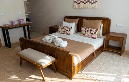 a bedroom with a large wooden bed with towels on it at Dar Eddihi Essaouira in Essaouira