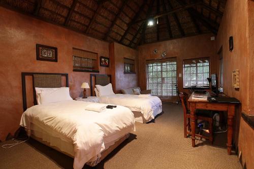 a bedroom with two beds and a desk with a computer at Gender Links Cottages in Johannesburg