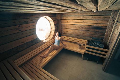 a woman sitting on a wooden bench in front of a window at Hotel Pashmina Le Refuge in Val Thorens