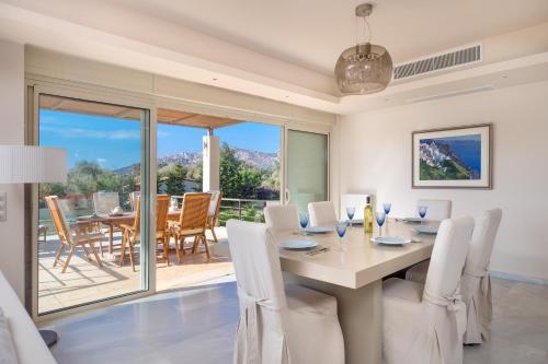 una sala da pranzo con tavolo e sedie e un balcone di Legrena Beach Villa a Sounio